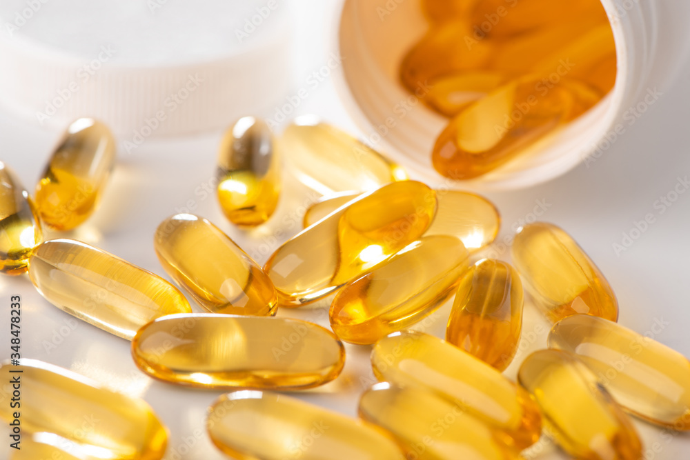 Close-up on cod liver oil capsules scattered from a bottle on white background Close-up on cod liver oil capsules scattered from a bottle on white background