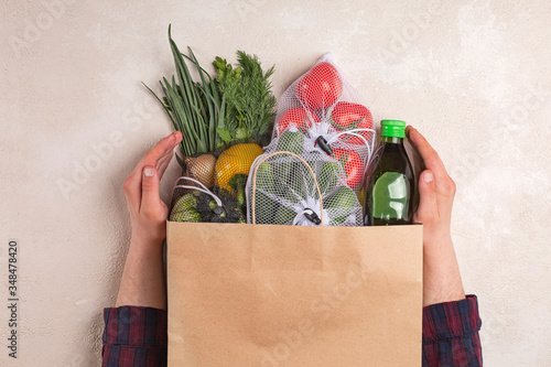 Man holds products in a paper bag. Vegetables in the range of shopping in the terrestrial and online store.