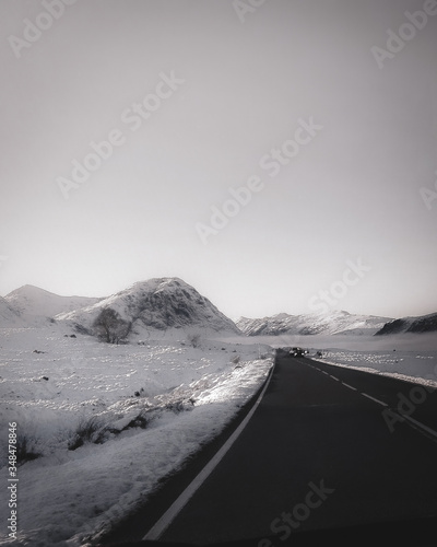 Cinematic snowy white road in Scotland showing road and mountian hills