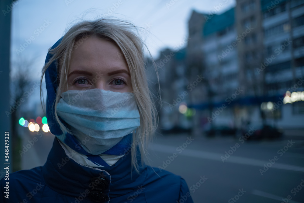 young blonde woman with a stole on her head in a medical mask close-up on a street in the city. Prevention of the spread of the flu virus. young blonde woman with a stole on her head in a medical mask close-up on a street in the city. Prevention of the spread of the flu virus.