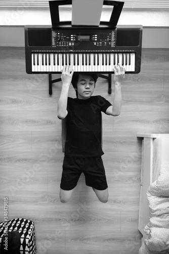 Fotografija Young Asian boy experimenting with the keyboard while in quarantine during COVID