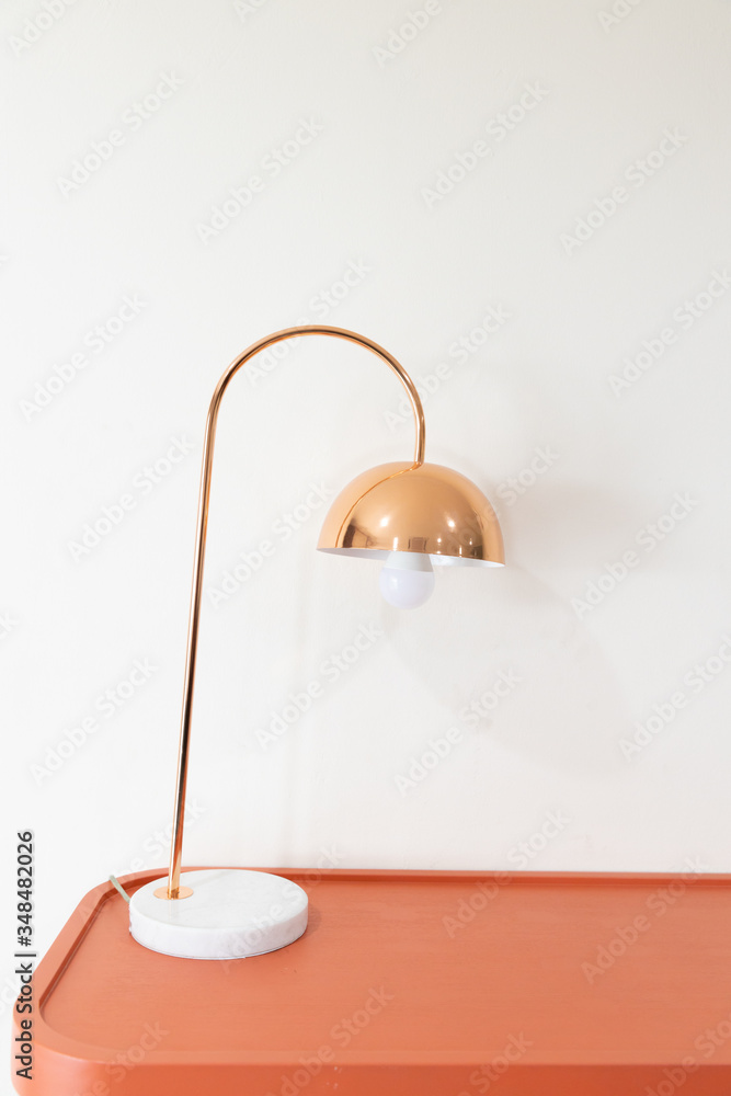 close up view of metal electrical table lamp with light bulb on the wooden orange desk close up view of metal electrical table lamp with light bulb on the wooden orange desk