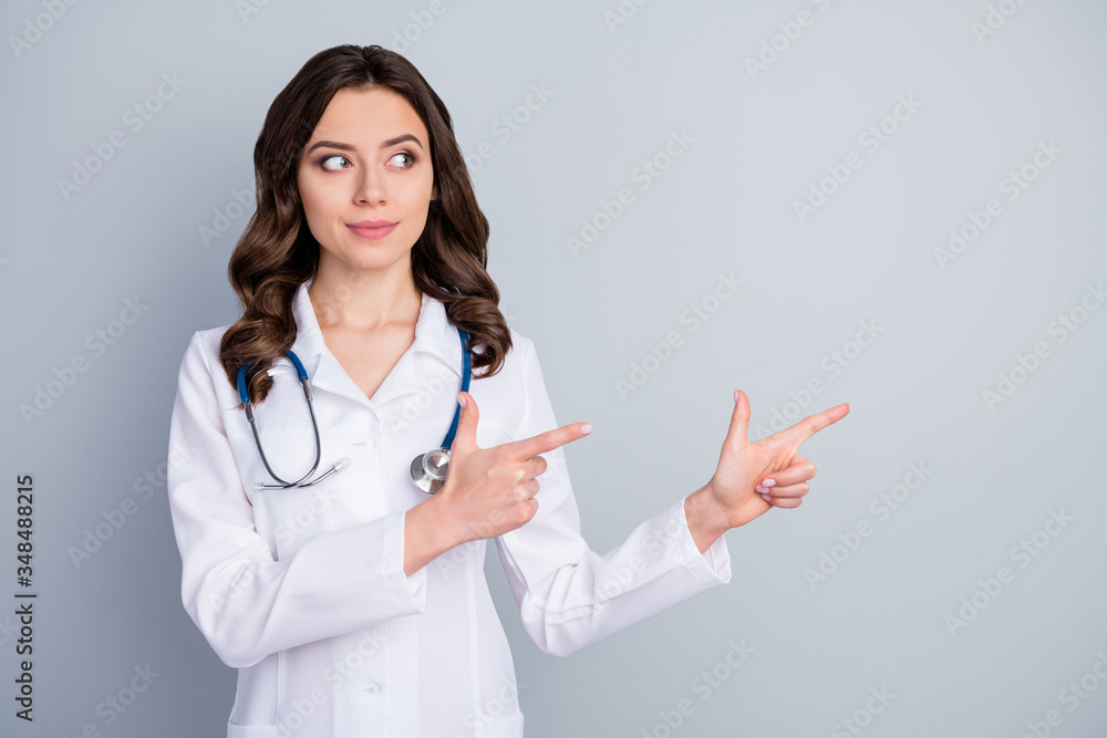 Photo of beautiful doc lady virologist direct fingers empty space show pandemic rules disinfection avoid respiratory symptom illness wear lab coat stethoscope isolated grey color background Photo of beautiful doc lady virologist direct fingers empty space show pandemic rules disinfection avoid respiratory symptom illness wear lab coat stethoscope isolated grey color background