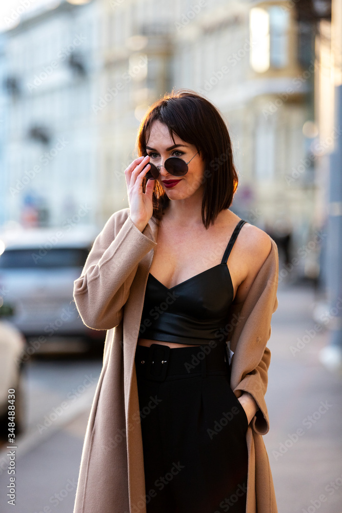 Fototapeta premium Woman in black pantsuit walks on promenade