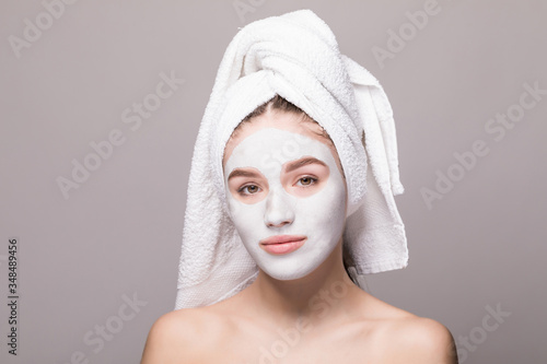 Beauty portrait of woman in towel on head with white nourishing mask or creme on face  white background isolated. Skincare cleansing eco organic cosmetic spa relax concept