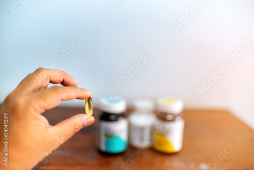 Hand holding Fish oil capsules with blurred background , Cod liver oil omega 3 gel capsules, Vitamin And Dietary Supplements, Selective focus.Healthcare concept.