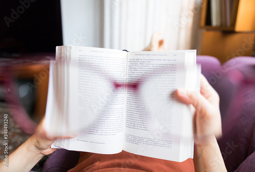 Mujer con gafas en cuarentena leyendo un libro tumbada en el sofá POV