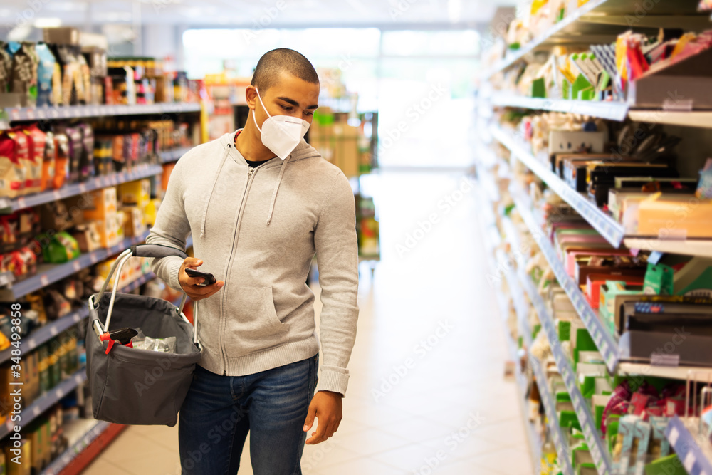 Einkaufen zur Zeit des Coronavirus, Mann mit Atemmaske in einem Supermarkt  