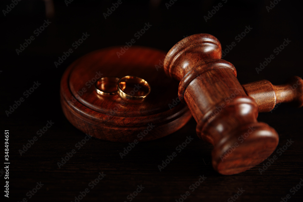 Wedding rings on the stand from a tree, hammer of a judge on a wooden background. Divorce divorce proceedings. Wedding rings on the stand from a tree, hammer of a judge on a wooden background. Divorce divorce proceedings.