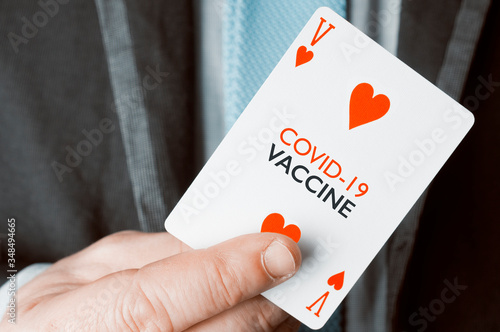 Covid-19 vaccine concept: a man in suit and tie show a playing card with the text covid-19 vaccine