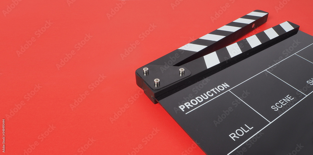 Black Clapperboard or movie slate on red background.it is used in video production and film industry .
