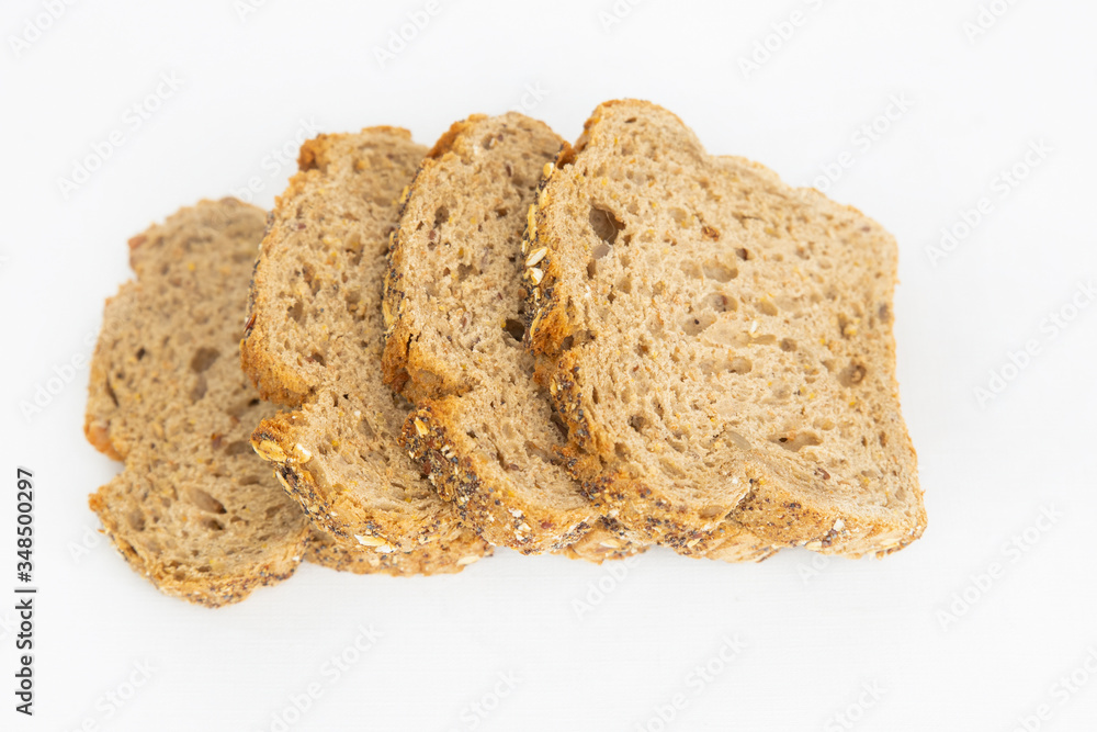 Four sliced pieces of cereal bread laying at table. Fresh homemade loaf cutting for eating isolated on white background. Studio shot. Top view. Cooking and baking at home concept Four sliced pieces of cereal bread laying at table. Fresh homemade loaf cutting for eating isolated on white background. Studio shot. Top view. Cooking and baking at home concept