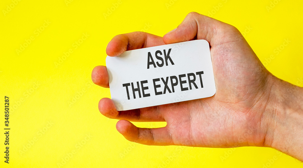 Businessman holds a card with the text ask the expert on a yellow background Businessman holds a card with the text ask the expert on a yellow background