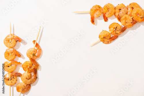 top view of delicious fried prawns on skewers on white background