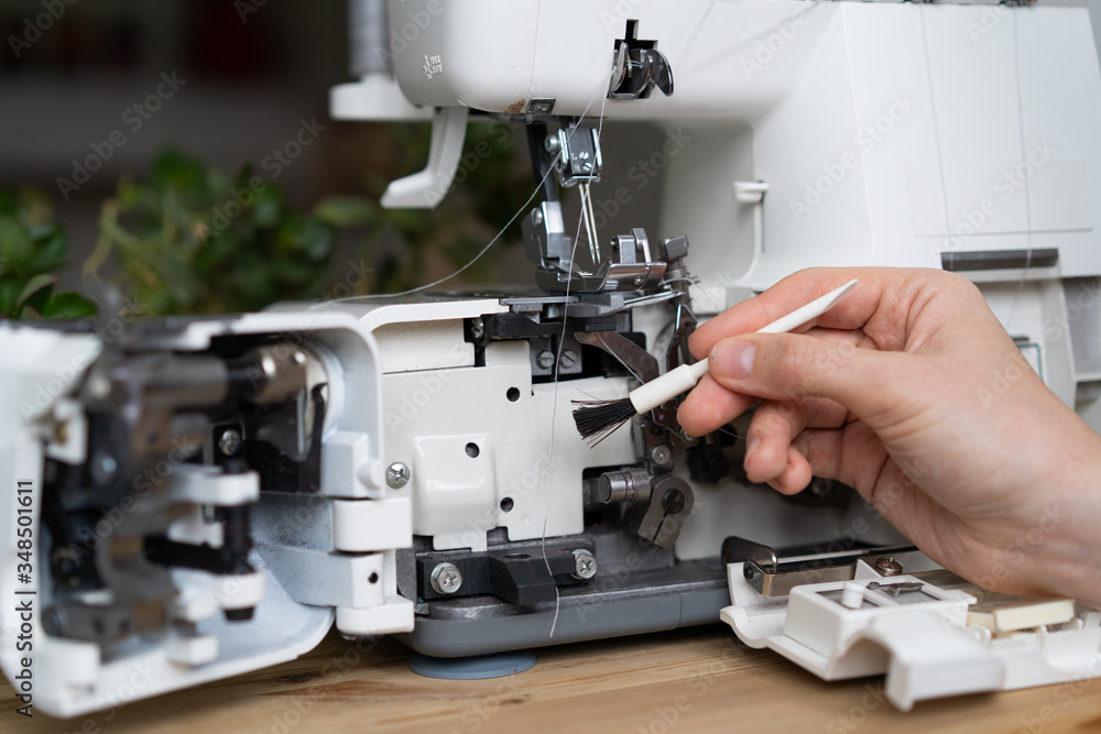 repair of sewing equipment, overlock. hand and a screwdriver fixes the breakage sewing machine