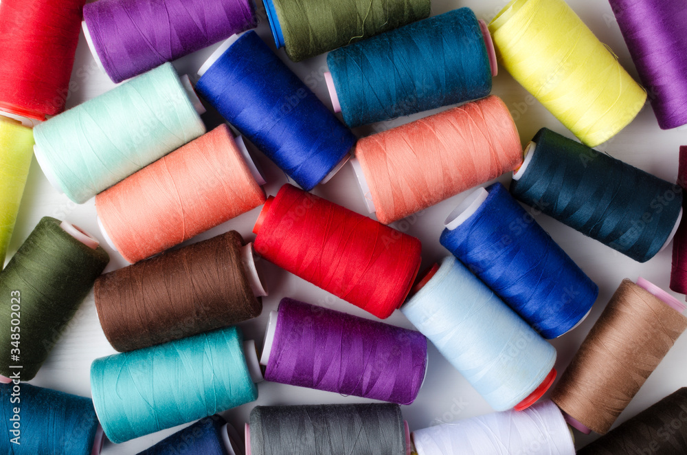 Top view of colorful bobbins on the white surface.Different colors of spools of thread Top view of colorful bobbins on the white surface.Different colors of spools of thread