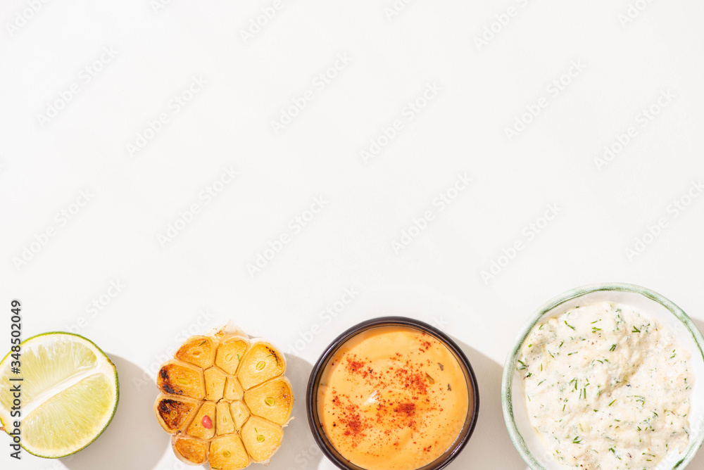 top view of garlic, lime and sauces on white background top view of garlic, lime and sauces on white background