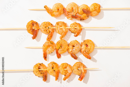 top view of prawns on skewers on white background