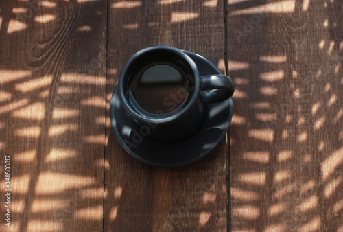 Cup of espresso on brown wooden table with shadows. Coffee shop, cafe, morning, breakfast, drink concept