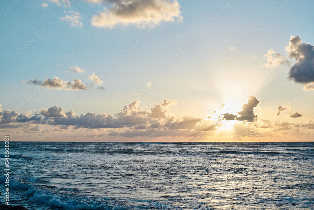 Sunset at the sea. Turquoise water in the ocean in the evening. Yellow sky with small clouds and blue waves at sandy beach at the seaside. Paradise resort landscape.Tropical resort travel picture. Sunset at the sea. Turquoise water in the ocean in the evening. Yellow sky with small clouds and blue waves at sandy beach at the seaside. Paradise resort landscape.Tropical resort travel picture.
