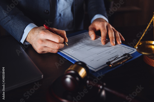 Man lawyer working with paper contract. Wooden gavel and libra on the desk