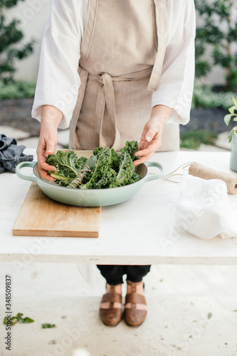 Female chef preparing a fresh kale dish in the vegetable garden photo