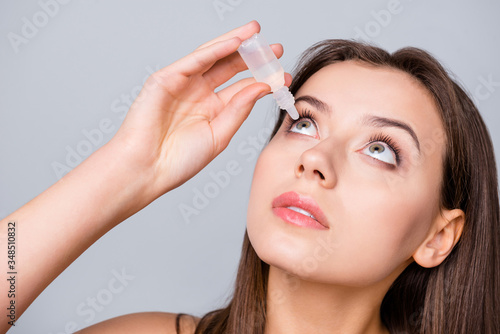 Close up photo of charming girl want cure her myopia refresh eye use eye dropper isolated over gray color background