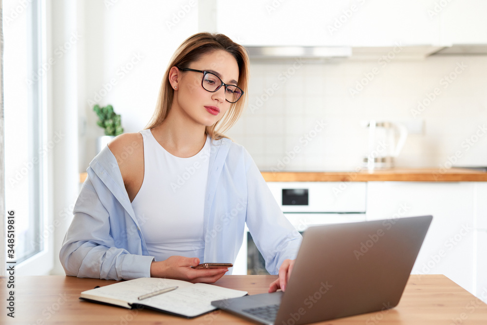 Beautiful student studying on line and learning writing notes in a desk at home. Working with laptop. Online studing courses