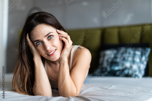 Portrait of young smiling woman lying on bed