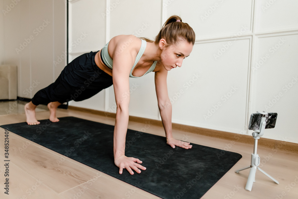 woman doing sport workout at home via online live training on phone woman doing sport workout at home via online live training on phone