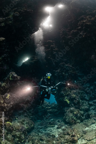 typical underwater cave in a red sea reef with an underwater photographer diver