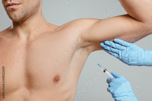 Cropped view of doctor doing botox injection from hyperhidrosis to man isolated on grey photo