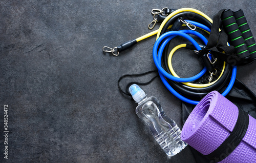 Sports accessories - expander with a carbine, water and mat on a black background.