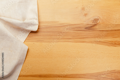 Top view on a wooden table with a linen kitchen towel or textile napkin.