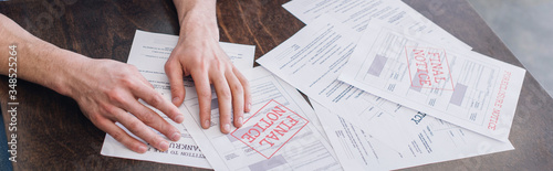 Cropped view of male hands near documents with foreclosure and final notice lettering on table, panoramic shot