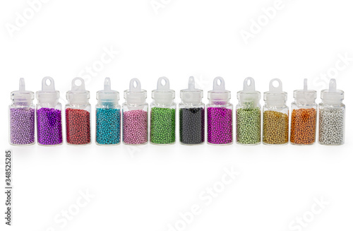 Beads different colorsr in bottles for the design of nails. White background. photo