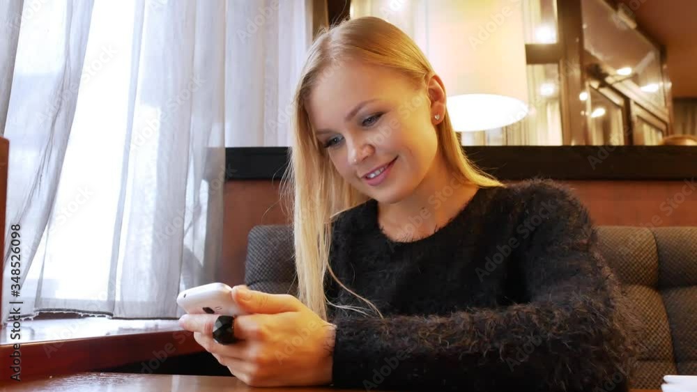 Beautiful attractive pretty girl in a good mood communicates on the phone in a cafe. Close-up. Beautiful attractive pretty girl in a good mood communicates on the phone in a cafe. Close-up.