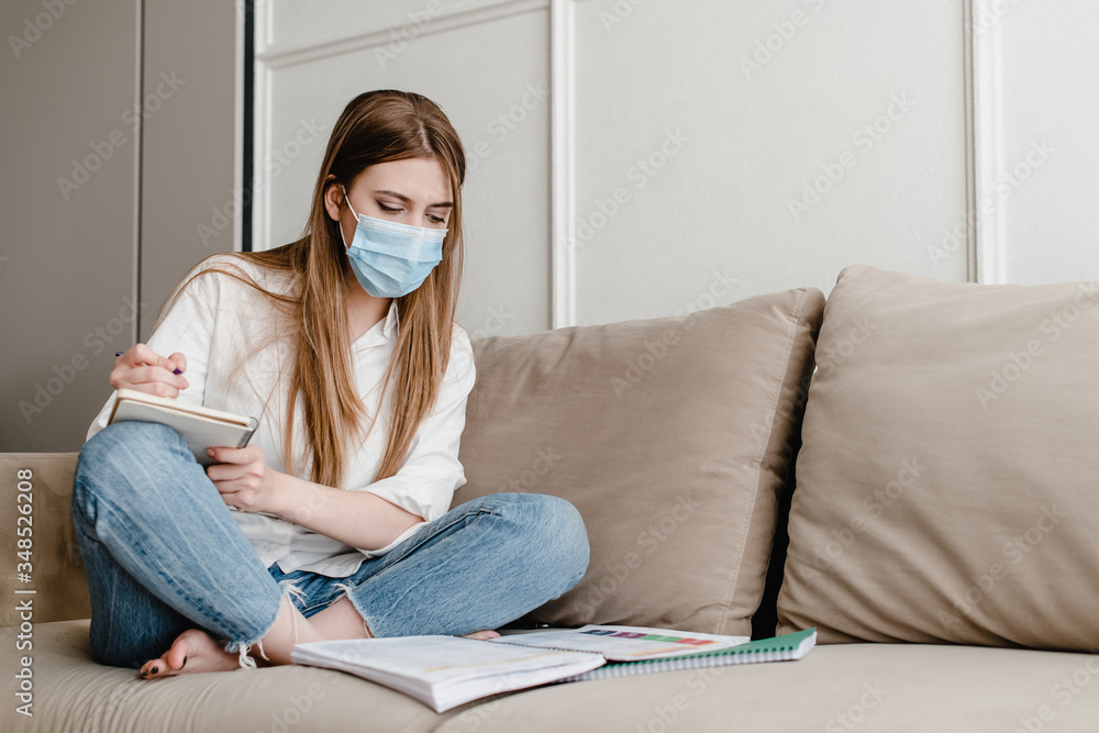 woman at home on couch wearing mask studying with books and notebook woman at home on couch wearing mask studying with books and notebook