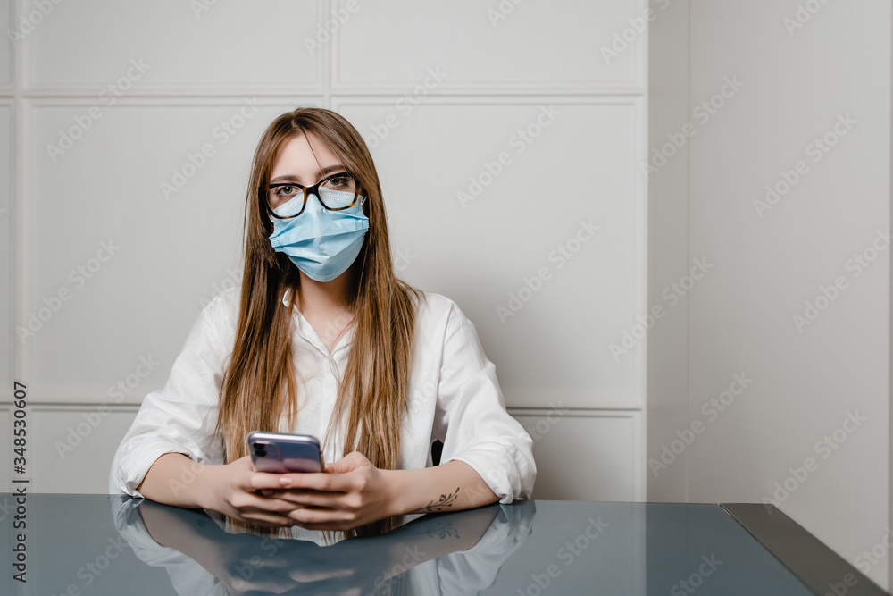 woman at home office wearing mask and using phone