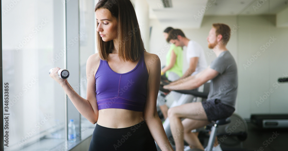 Young beautiful woman doing exercises with dumbbell in gym Young beautiful woman doing exercises with dumbbell in gym
