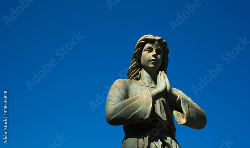 Angel statue in prayer and blue sky