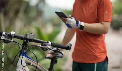 Cyclist use smartphone when riding mountain bike on forest trail