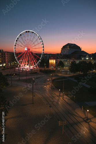Dresden at dawn. View of the ferris wheel and deserted evening streets and tram tracks at sunrise. Tourism in Dresden. Night landscape Dresden, German. Tourism in Europe. Vertical