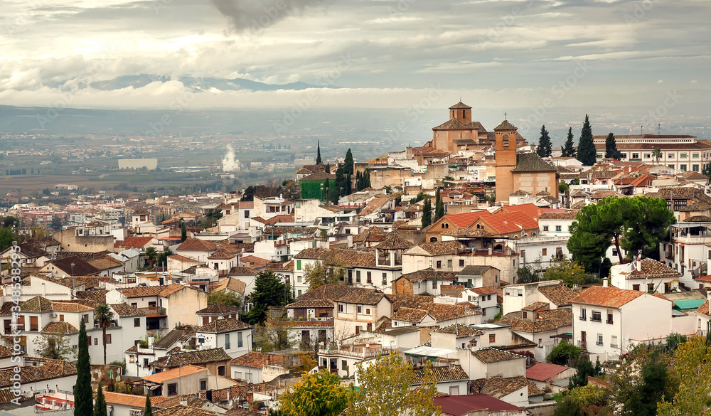 Cityscape with old houses of Granada under rainy clouds. Landscape of historical town of Andalusia, Spain.