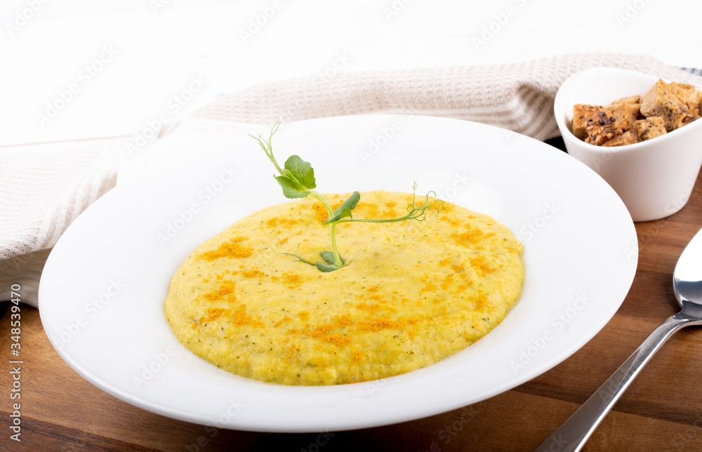 Mixed vegetable cream soup in a white bowl, isolated on a white background, on wooden cutting board