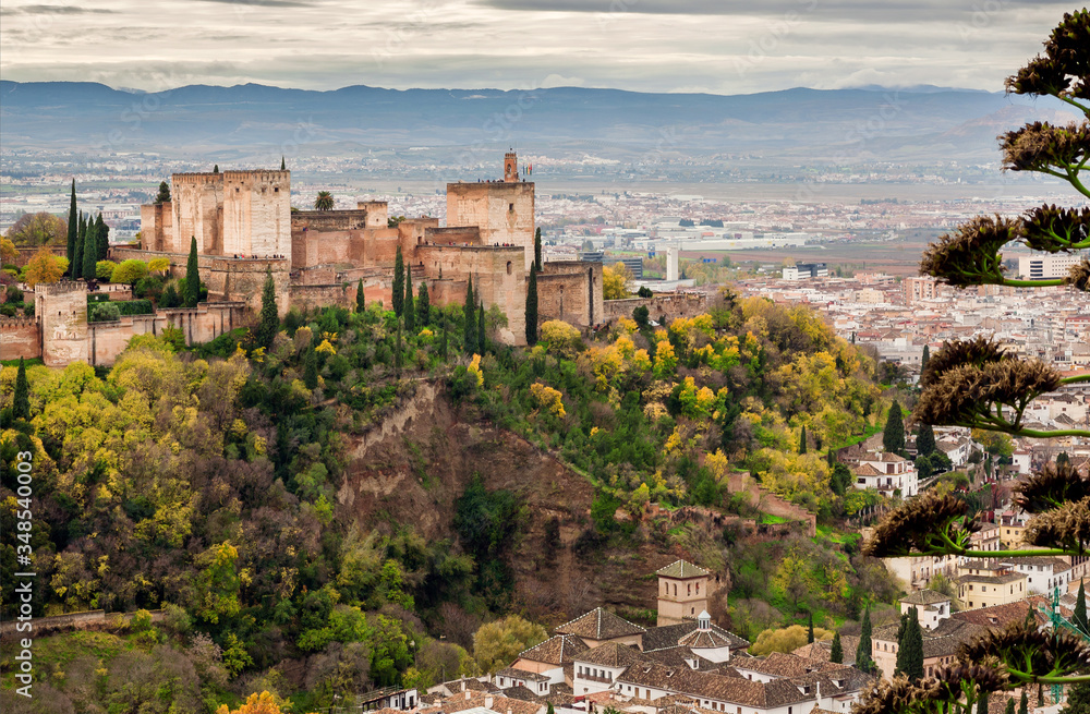 Alhambra castle on green hill at autumn. Old structures of Granada . View of historical town of Andalusia, Spain.