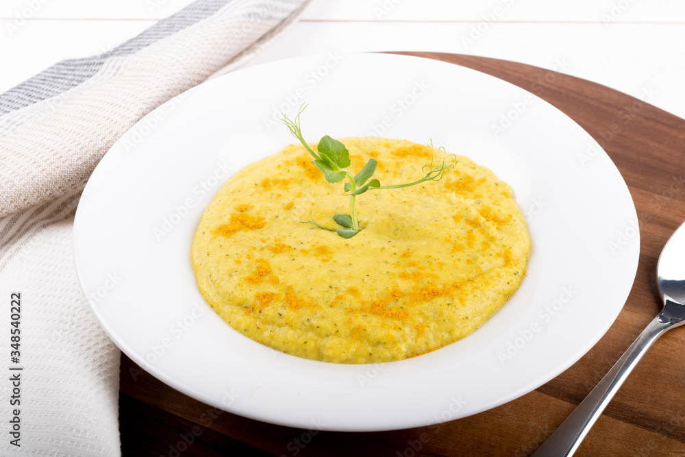 Mixed vegetable cream soup in a white bowl, isolated on a white background, on wooden cutting board Mixed vegetable cream soup in a white bowl, isolated on a white background, on wooden cutting board
