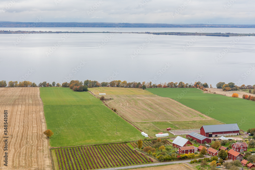 Naklejka premium View of Lake Vattern with a picturesque little Swedish village and the plowed field on the coast photographed from the fortress Brahehus in Granna, Jonkoping, Sweden.