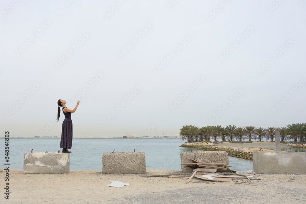 Woman with long dress standing on stone looking up to white sky background. Woman with long dress standing on stone looking up to white sky background.