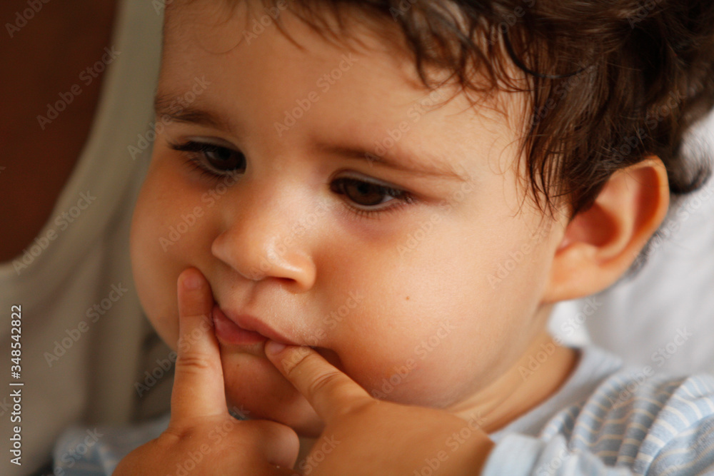 baby with confused look and little fingers in mouth, narrow focus baby with confused look and little fingers in mouth, narrow focus